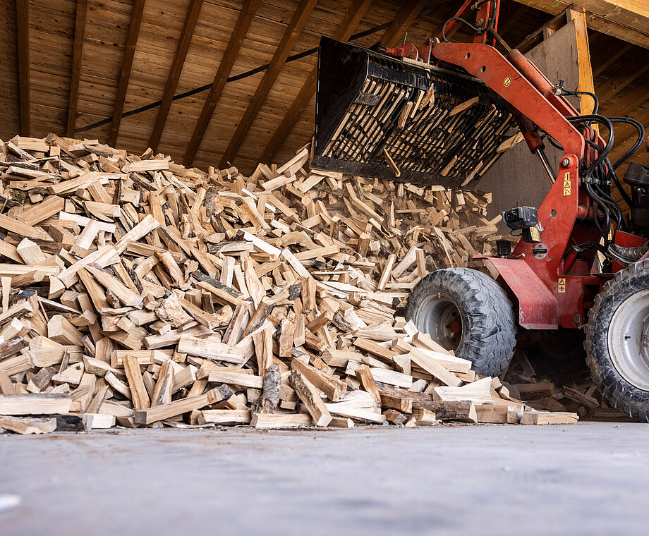 Holzscheite werden auf Stapel abgeladen.