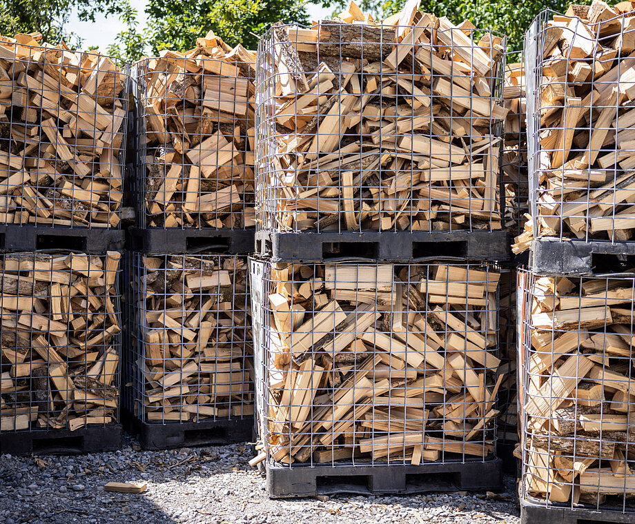Gespaltenes Brennholz wird in großen Gitterboxen gelagert und für Abholung oder Lieferung vorbereitet.